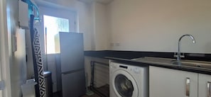 Une cuisine de taille réduite équipée d’un lave-linge, d’un réfrigérateur et d’un évier.
