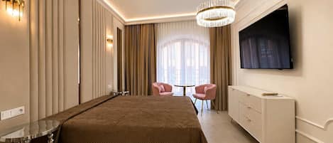 A modern bedroom with a large bed, a TV mounted on the wall, and a chandelier.