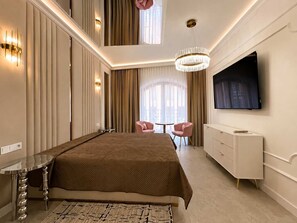 Ein modernes Schlafzimmer mit einem großen Bett, einem an der Wand montierten Fernseher und einer Kandelaberleuchte.