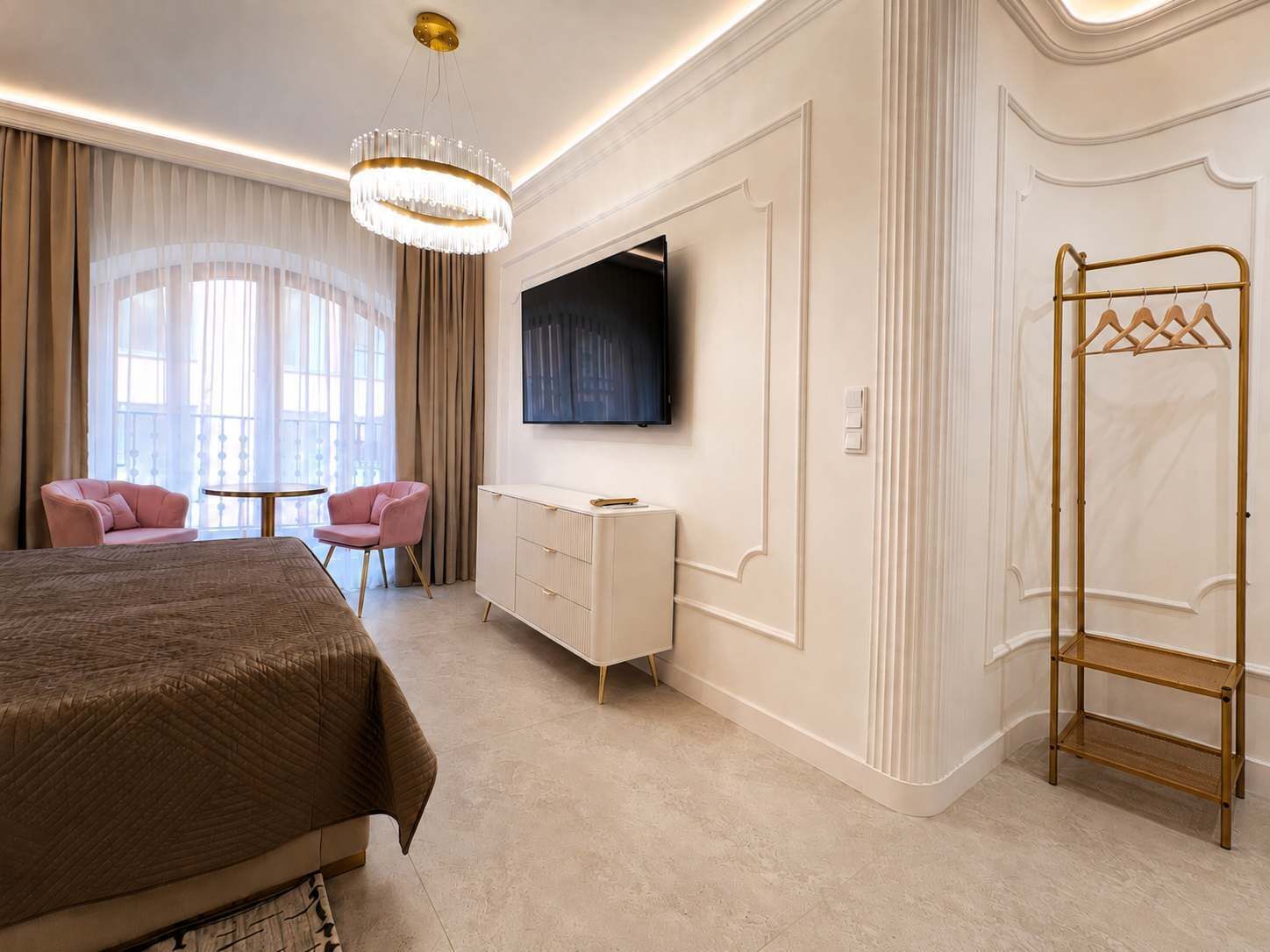 Ett hotellrum med en säng, ett skrivbord, en tv, en garderob och ett fönster med gardiner.