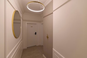 Ein Flur mit einer Tür, einem runden Spiegel und einer modernen Lampe.
