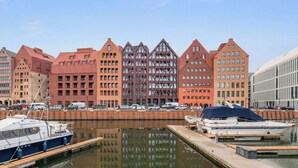 Ein Yachthafen mit vertäuten Booten, ein großes, rot gefärbtes Gebäude im modernen Stil und ein klarer Himmel.