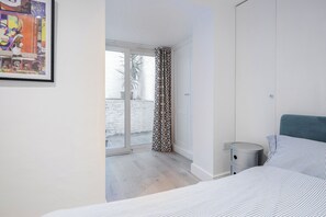 Ett modernt sovrum med en säng, ett sängbord och ett stort fönster med utsikt över ett snötäckt område utomhus.