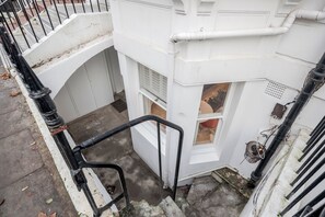 A narrow stairway leading to a white building with a window and a door. - Stylish Chelsea Apartment | 2 Bedrooms | Patio Living (London)