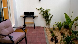 A patio with a chair, a small table with a laptop, and potted plants.