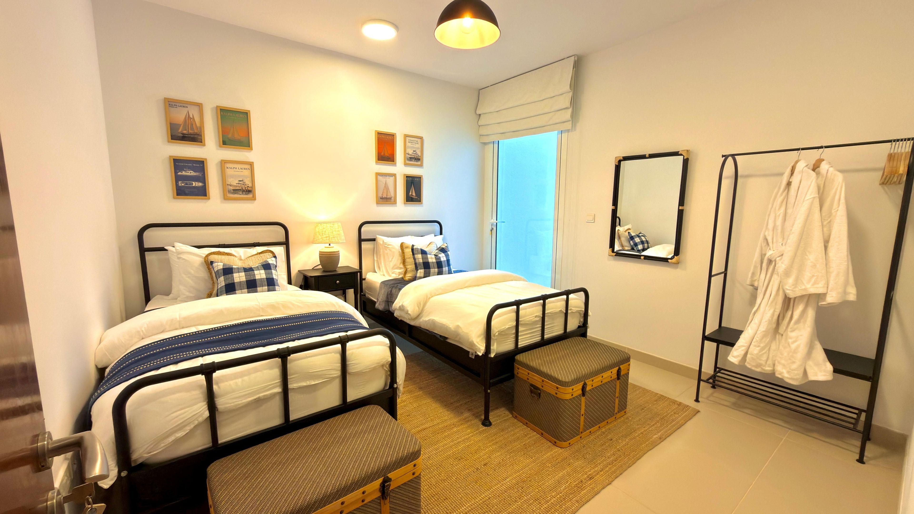 Ein Hotelzimmer mit zwei Betten, einer Sitzecke, einem Spiegel und einem Kleiderhaken.