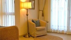 A room with a sofa, a floor lamp, a chair with a cushion, a woven basket, and a large window with curtains. - 4BR Blue Palm Villa near Al Bustan Beach (Al-Bustan)