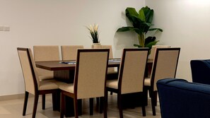 A dining area with a table and chairs, a potted plant, and a blue sofa.