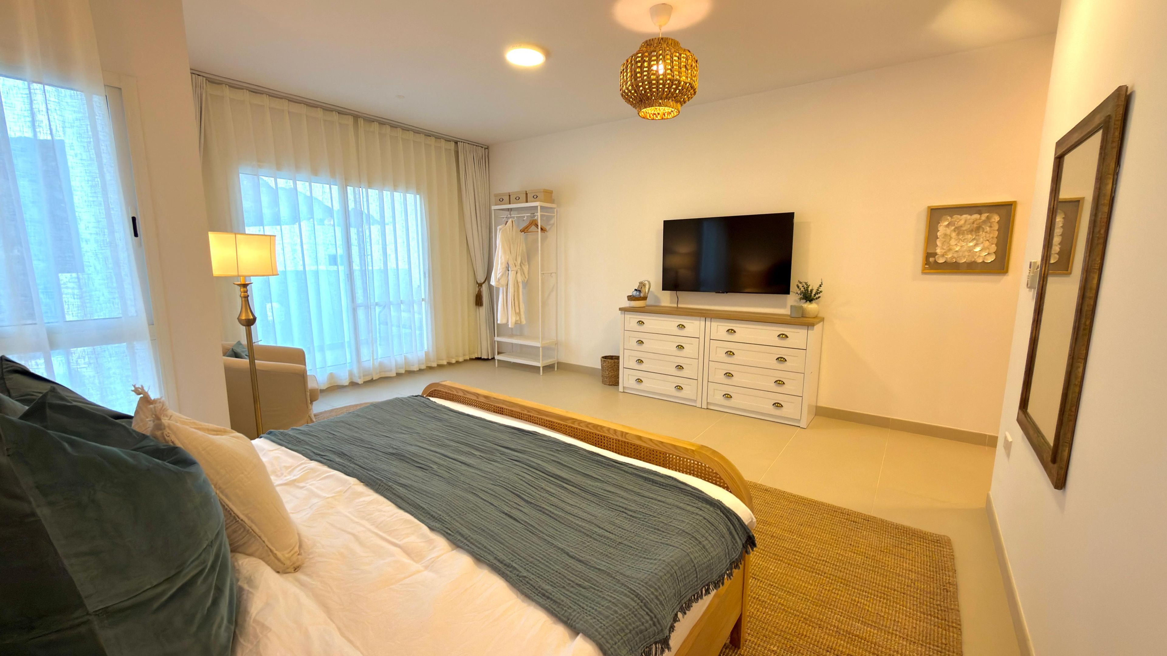 A hotel room with a bed, a TV, a wardrobe, and a window with curtains.