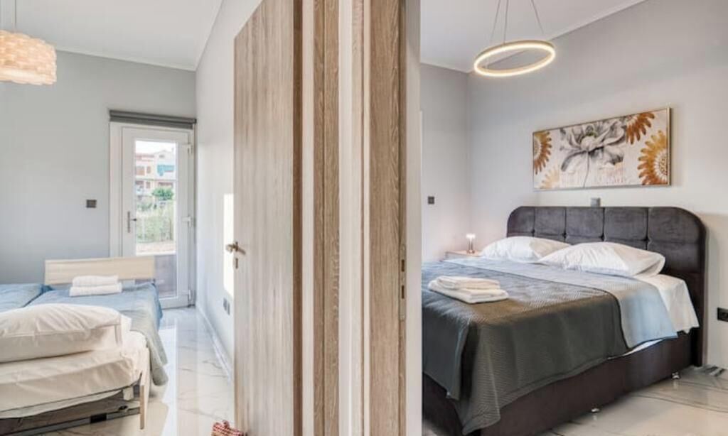 A modern bedroom with a large bed, a bedside table, and a hanging light fixture.