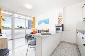 A modern kitchen with a dining area, a view of the sea, and a surf-themed decoration. - Quiet, comfortable apartment just 5 minutes from Yumbo (Maspalomas)