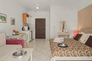 Habitació d'hotel amb llit, escriptori, cuina americana i bany.