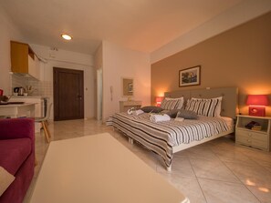A bedroom with a bed, bedside tables, a nightstand, a desk, and a chair.