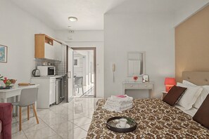 Una habitación de hotel con cama, escritorio, kitchenette y baño.