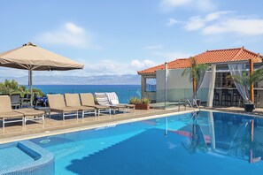Zona junto a la piscina con sillones, una piscina y vista al mar.