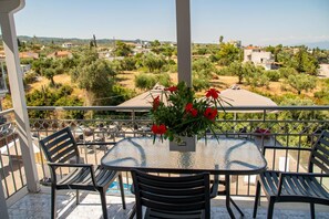 Un balcón con una mesa redonda y cuatro sillas, con vistas a una zona residencial con casas y vegetación.