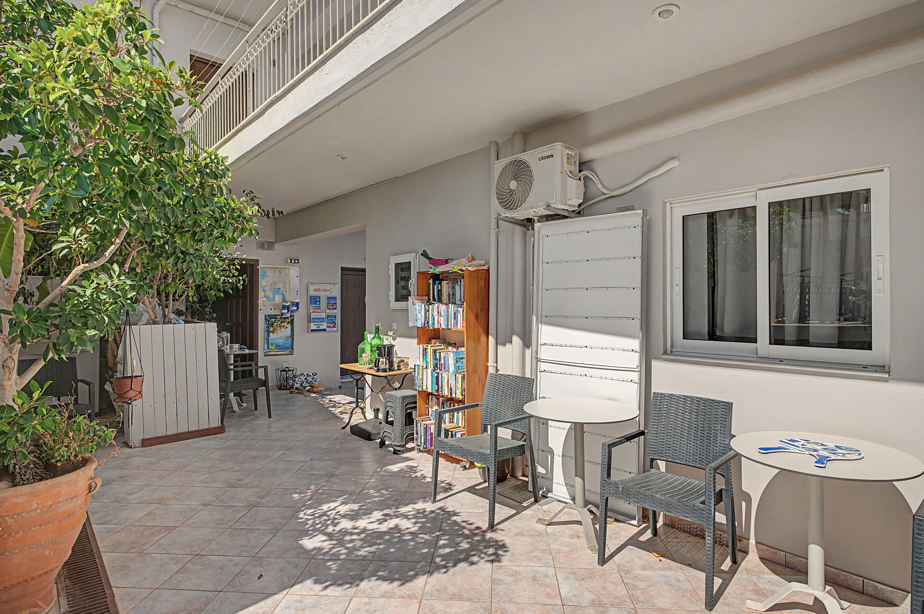 A sunlit outdoor patio with a seating area, a bookshelf, and a map on the wall.