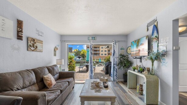 A living room with a brown leather sofa, a coffee table, and a view of an outdoor pool area.