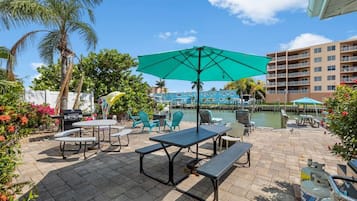 Un espace extérieur aménagé en terrasse, avec des tables, des chaises et un grand parasol.