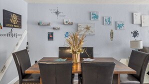 A dining area with a wooden table and chairs, surrounded by decorative wall art and a compass.