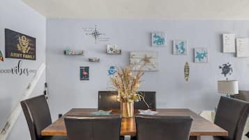 Un coin repas avec une table en bois et des chaises noires, agrémenté de décorations murales et d’une boussole.