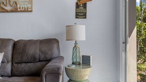A room with a leather sofa, a lamp on a small table, and decorative signs on the wall.
