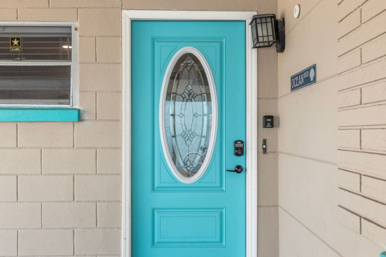 A turquoise door with a glass panel, a keypad lock, and a small sign above it.