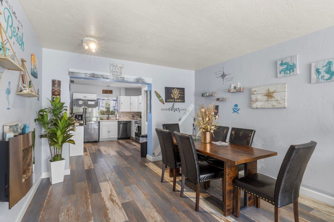 A modern kitchen with white cabinets and stainless steel appliances, leading to a dining area with a wooden table and black chairs.