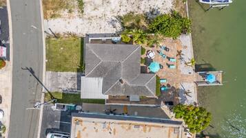 An aerial view of a property with a dock, boats, and a building with a tiled roof.