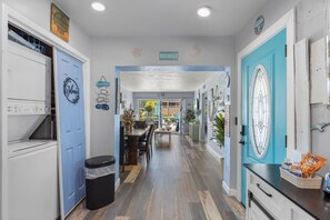 A hallway with a kitchen area on the left, a dining area in the center, and a bathroom on the right. - WTR FRONT Home W/Dock | Steps to the Beach! (Treasure Island)