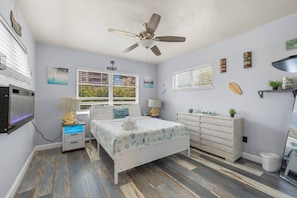 A bedroom with a bed, a ceiling fan, a dresser, a vanity, and a window with blinds. - WTR FRONT Home W/Dock | Steps to the Beach! (Treasure Island)