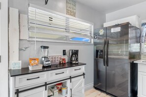A kitchen with a stainless steel refrigerator, a coffee maker, a blender, and a sign that says 'Coffee Salt Air.'