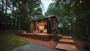 A modern cabin with a deck, surrounded by trees. - Highland Cottages at Lake Guntersville (Guntersville)