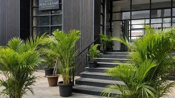 En hotelindgang med et skilt for 'Pune Grand Hotel', en trappe og plantekasser.