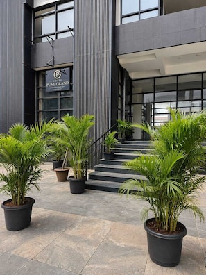 A hotel entrance with a sign for 'Pune Grand Hotel,' a staircase, and potted plants.