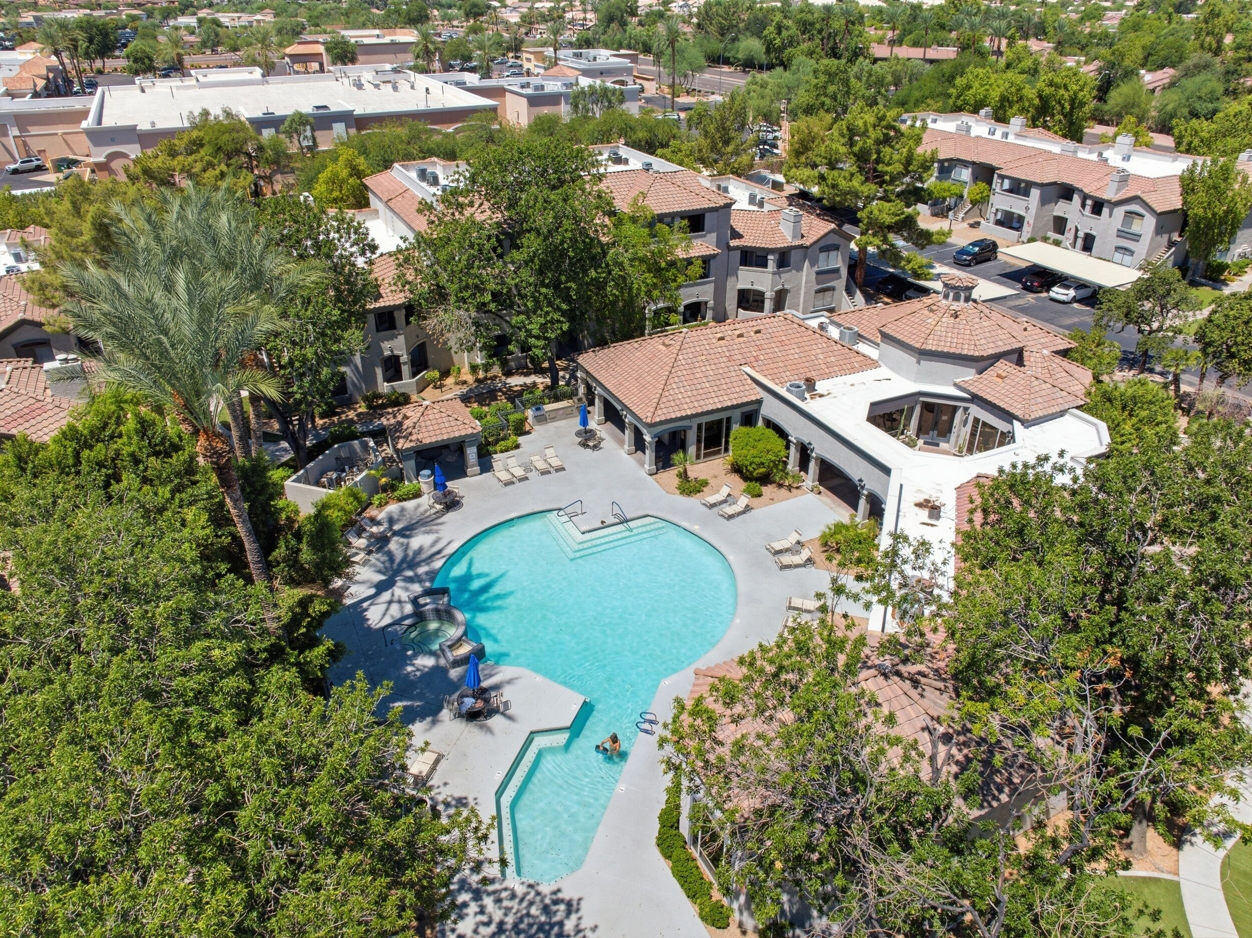 A residential area with a swimming pool surrounded by lounge chairs and umbrellas, indicating a resort-like setting.