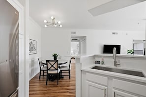 A modern kitchen with white cabinetry, a built-in sink, and a dining area with a table and chairs. - North Scottsdale Retreat with Mountain Views & 2 Pools (Scottsdale)
