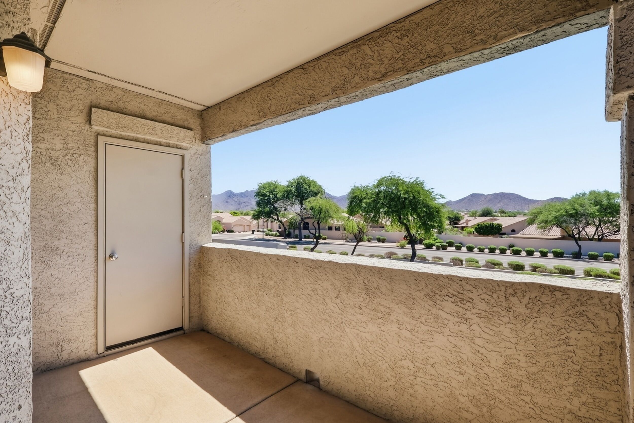 Ein Balkon mit Blick auf eine Wüstenlandschaft, eine Tür und eine strukturierte Wand.