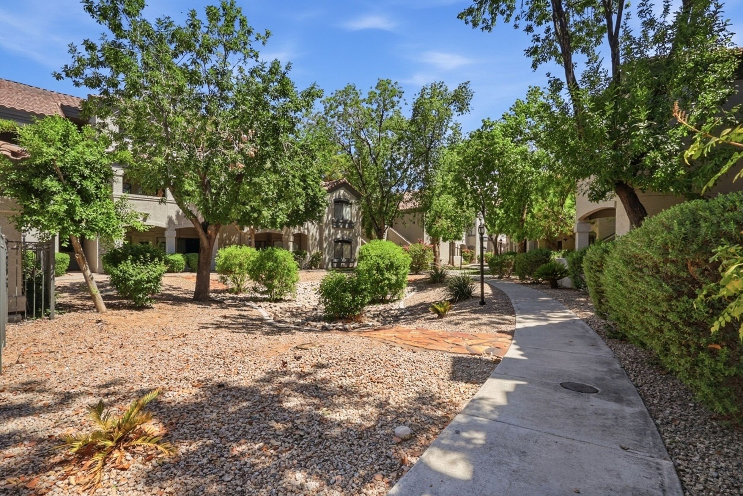 Un quartier résidentiel avec un chemin de gravier, des arbres et des maisons présentant un style architectural uniforme.
