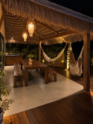 An outdoor dining area with a wooden table and benches, a thatched roof, and hanging hammocks. - Villa 60 meters from the lagoon / Kitesurfing / Wingfoiling (ITAREMA)