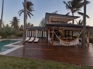 Ein modernes Haus mit Swimmingpool, Außenbereich und einer Hängematte.