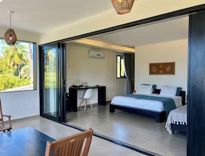 A modern hotel room with a large bed, a desk, and a view of palm trees.