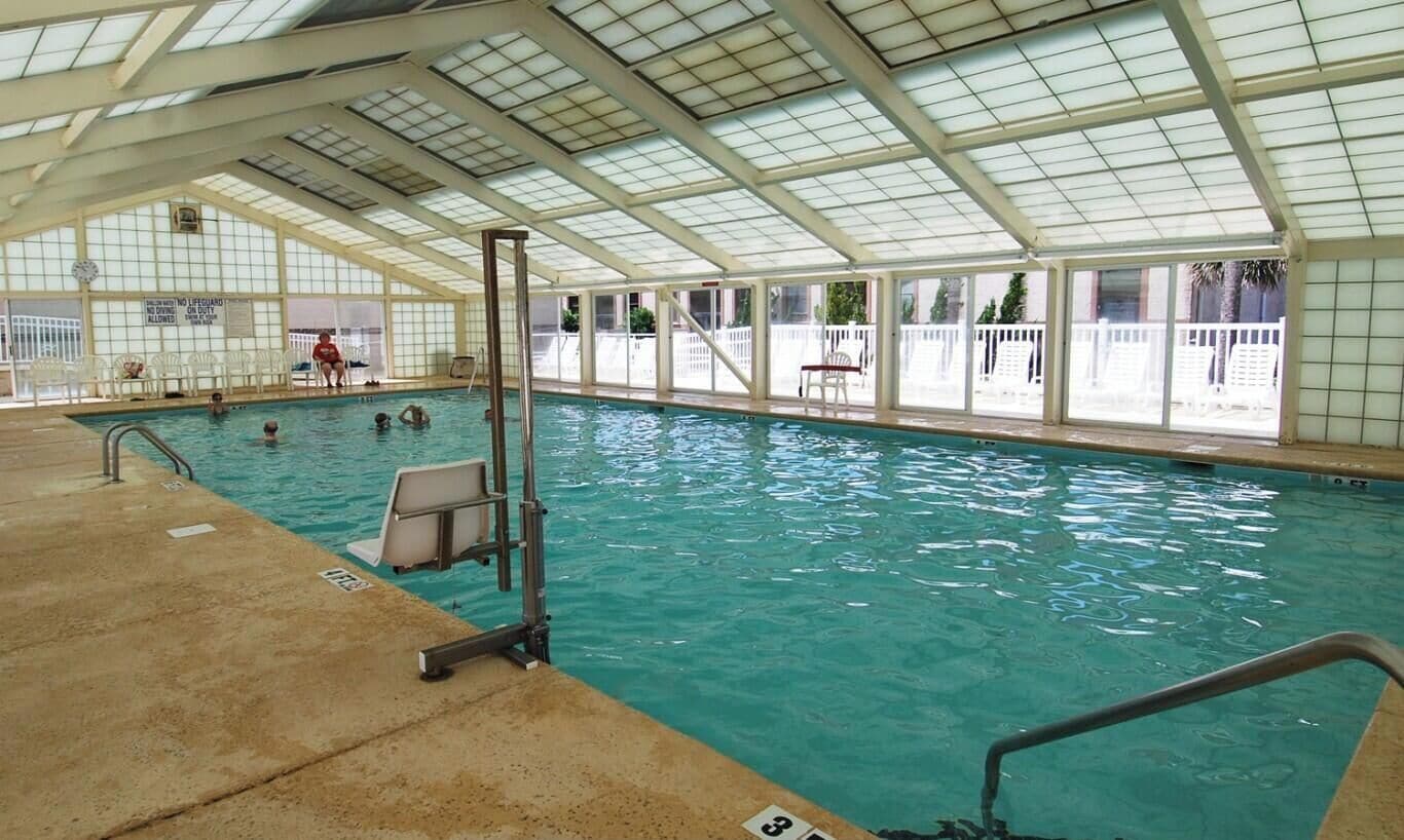 En inomhuspool med ett glastak, klart vatten och en livräddarstation.