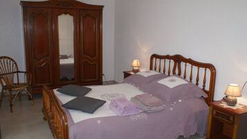 Ein Schlafzimmer mit einem Bett, zwei Nachttischen, einem Holzschrank, einem Sessel und einem Spiegel.