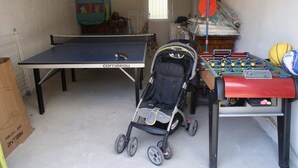 Una stanza con tavolo da ping pong, tavolo da calcio e passeggino.
