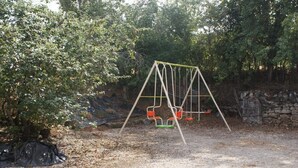 Un'area giochi con altalene e un muro in pietra sullo sfondo.