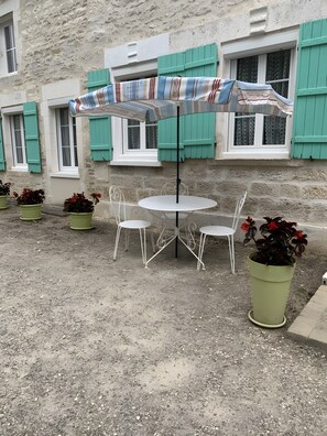 An outdoor seating area with a round table and four chairs, surrounded by potted plants.
