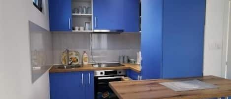 A modern kitchen with blue cabinets, a wooden countertop, and a built-in oven.