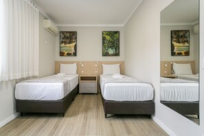 Une chambre d’hôtel avec deux lits, une table de chevet et un miroir.