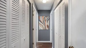 A hallway with lockers on both sides, a wooden floor, and a wall with abstract art. - Sleek & Peaceful Retreat at Bailey Court #1 (El Dorado)